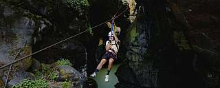 Rappelling in a narrow gorge with green water.