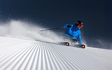 A skier glides with style over a freshly groomed snow slope.