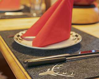 A set table with red napkins and cutlery on a felt placemat.