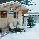 Holzhütte mit Fondue-Schild und winterlicher Dekoration.