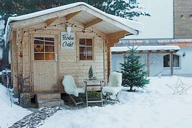 Wooden cabin with fondue sign and winter decoration.