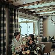 Ein Paar prostet sich mit Getränken in einem stilvollen Café zu.