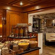 A buffet with various cereals and drinks in a wooden restaurant.