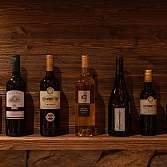 Eine Auswahl an Weinflaschen auf einem Holzregal.