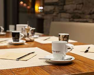 A table with several coffee cups and cutlery.