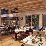 Cozy restaurant with tables, candles, and a view of the snowy landscape.