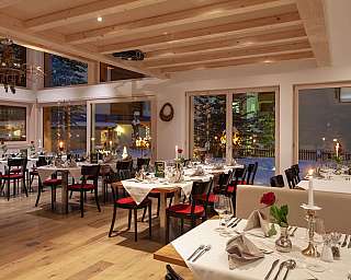 Gemütliches Restaurant mit gedeckten Tischen und Blick auf schneebedeckte Landschaft.