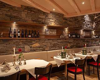 Elegante Tische mit Kerzen und Weinregal im Hintergrund.