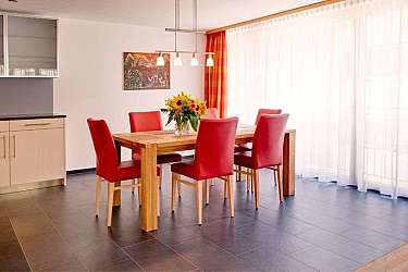 Ein Esszimmer mit einem Holztisch und roten Stühlen.