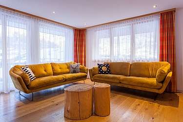 Helles Wohnzimmer mit gelben Sofas und Holztisch.