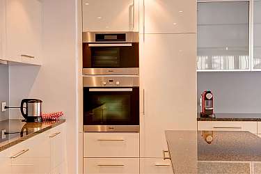 Küche mit Edelstahlöfen und Kaffeemaschine auf der Arbeitsplatte.