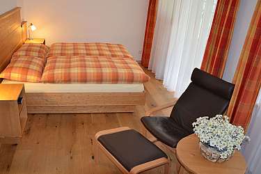 Ein Schlafzimmer mit einem Bett, Sessel und Holzboden.