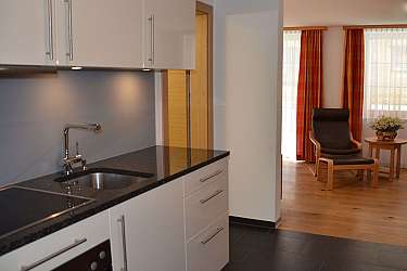 Helle Küche mit Essbereich und gemütlichem Sessel.