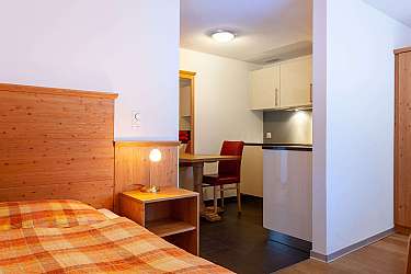 Ein Schlafzimmer mit Holzdetails und angrenzender Küchenzeile.