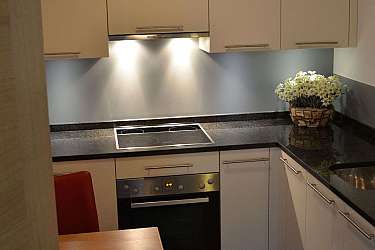 Kleine, moderne Küche mit Kochfeld und Esstisch.