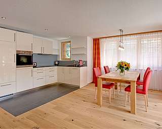 Helle Küche mit Holzfußboden und rotem Essbereich.