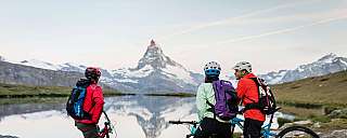 Trois vététistes profitent de la vue sur les montagnes et le lac.
