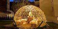 A lit igloo with seating and a table outdoors.
