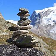 Eine Pyramide aus Steinen vor schneebedeckten Bergen.