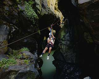 Rappelling in a narrow gorge with green water.