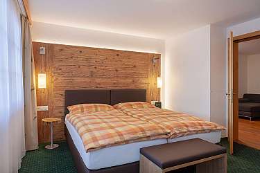 Schlafzimmer mit Doppelbett, Holzpaneel, zwei Hängelampen und grünem Teppich