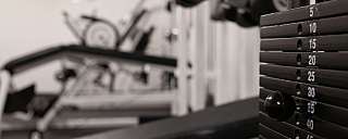 Nahaufnahme von Fitnessgeräten und Gewichtsstapel im Hintergrund.