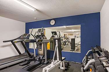 A fitness room with a treadmill, cross trainer, and weights.