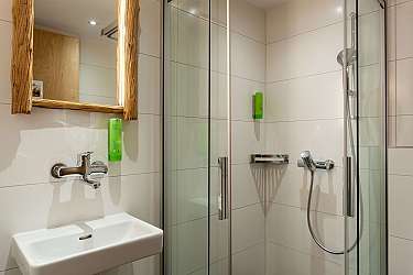 Bright bathroom with shower, sink, and wooden mirror.