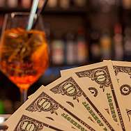 Ein Glas mit einem orangefarbenen Getränk und gefächerte Geldscheine.