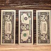 Drei dekorative Dollar-Scheine des Jägerhof Hotels auf Holzuntergrund.