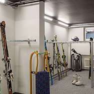 A ski room with skis, ski boots, and sledges.