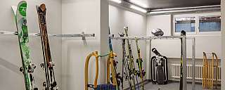 A ski room with skis, ski boots, and sledges.