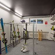 A ski room with skis, ski boots, and a sled.