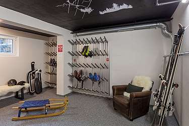 A ski room with skis, sledges, and seating.