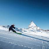Skifahrer fährt auf präparierter Piste mit Matterhorn im Hintergrund bei klarem Himmel