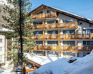 Moderne Unterkunft mit Balkonen in verschneiter Landschaft.