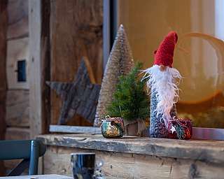 Ein Gnom und Weihnachtsbaumdekoration auf einer Holzfensterbank.