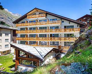 View of a modern hotel in the mountains with balconies.