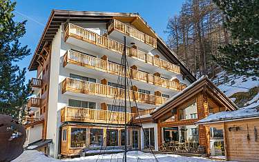 Ein modernes Hotelgebäude mit Holzverkleidung und Balkonen im Schnee.