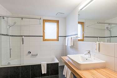 Bright bathroom with sink, bathtub, and towel rack.