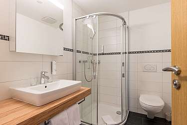 Bright bathroom with bathtub, shower, and wooden details.