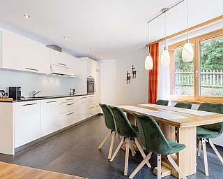 Bright kitchen with wooden floor and red dining area.