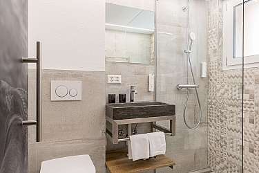 Modernes Badezimmer mit Dusche, Waschtisch und hellen Fliesen