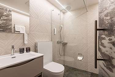 Modernes Badezimmer mit Dusche, Waschbecken, Toilette und hellen Fliesen