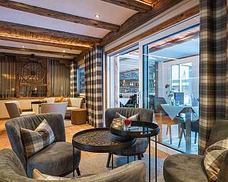 Gemütlicher Lounge-Bereich mit Sesseln, Tischen und rustikalen Holzbalken