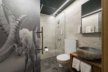 Un lavabo rustique en pierre naturelle sur une étagère en bois.