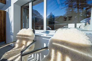 Un cœur à carreaux pend à un crochet devant un mur en bois.