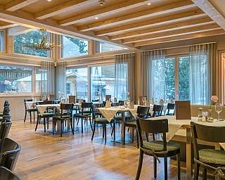 Helles Restaurant mit Holzbalkendecke, gedeckten Tischen und großen Fenstern