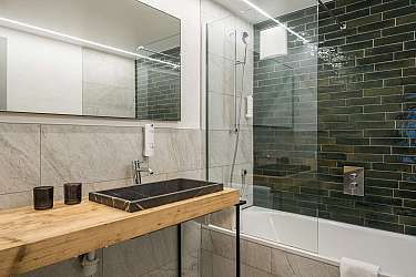 Modernes Bad mit Holzwaschtisch, schwarzem Waschbecken und Badewanne.