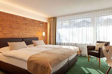 Ein helles Zimmer mit Doppelbett und gemütlichem Sessel.